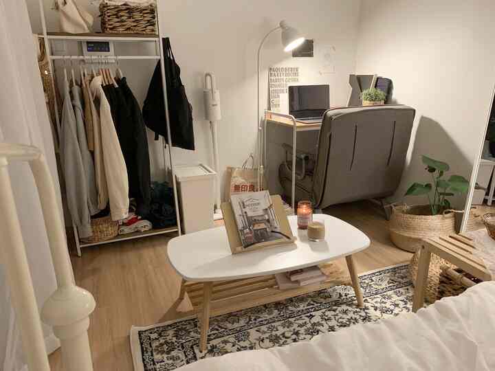 Natural wood tones and white dominate this studio apartment featuring a desk and chair, creating a cozy and functional home office and living area