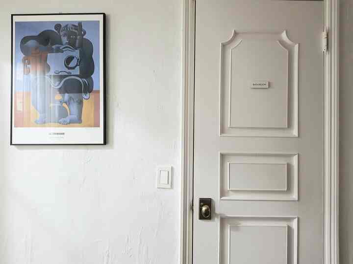 Bright ivory-toned wall and door with a Le Corbusier poster in a clean entrance space
