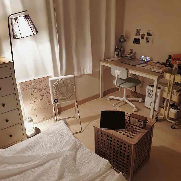 White curtains and brown wood tone furniture in a small single household room featuring a desk, office chair, and bed with a cozy atmosphere