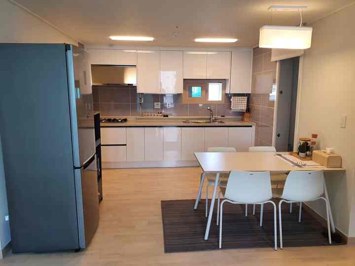 White and brown toned kitchen space featuring dining table with four chairs in a clean minimal style interior
