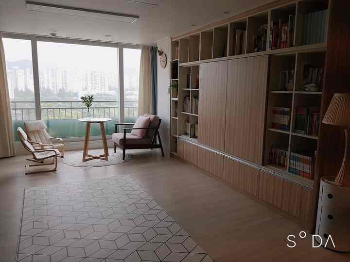 Beige and white toned living room and veranda space featuring a round table, armchairs, and a bookshelf creating a calm home cafe atmosphere