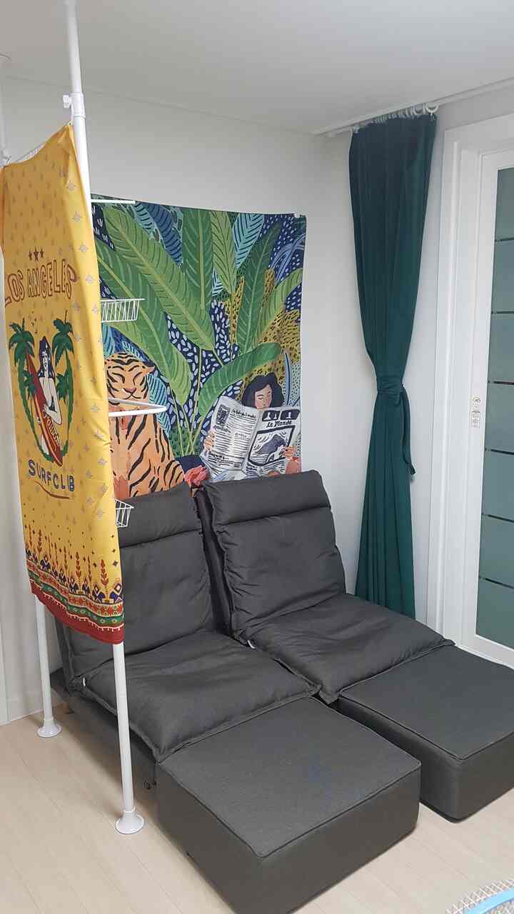 ダークグレーの座椅子とグリーンの遮光カーテン、ヴィンテージポスターが配置された居心地の良い趣味部屋