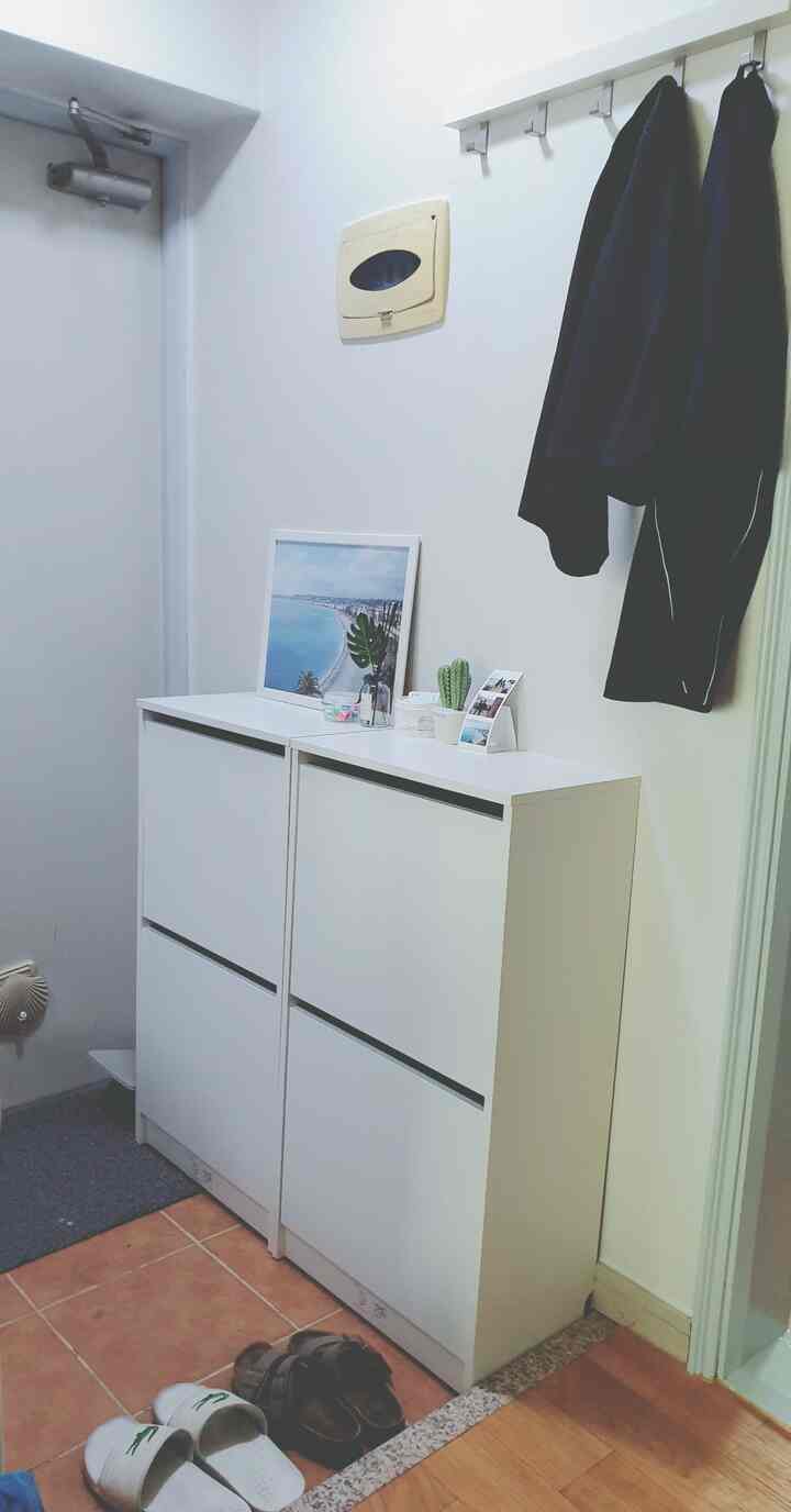 白色調の玄関、イケアのシューズラックが2台とシンプルな小物が配置されたすっきりとした空間