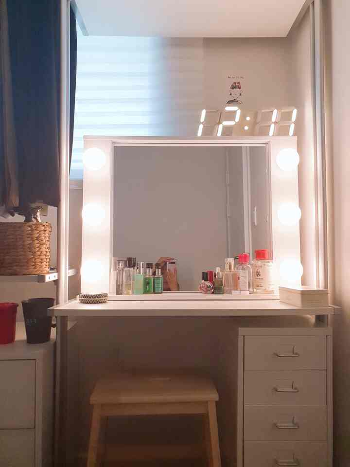 White-toned walk-in closet vanity with round light bulbs and LED digital clock, creating a clean and cozy space
