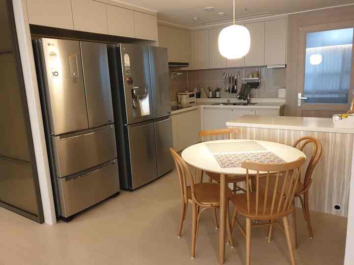 ホワイトと木目調が調和するコンパクトなキッチン、円形のダイニングテーブルと木製チェアが配置されたナチュラルモダンなインテリア