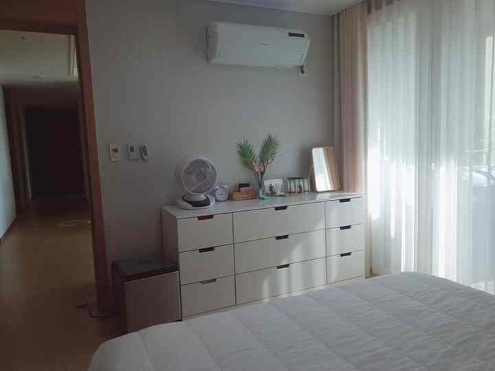 White-toned bedroom featuring a white dresser, white bedspread, and bright curtains creating a clean atmosphere