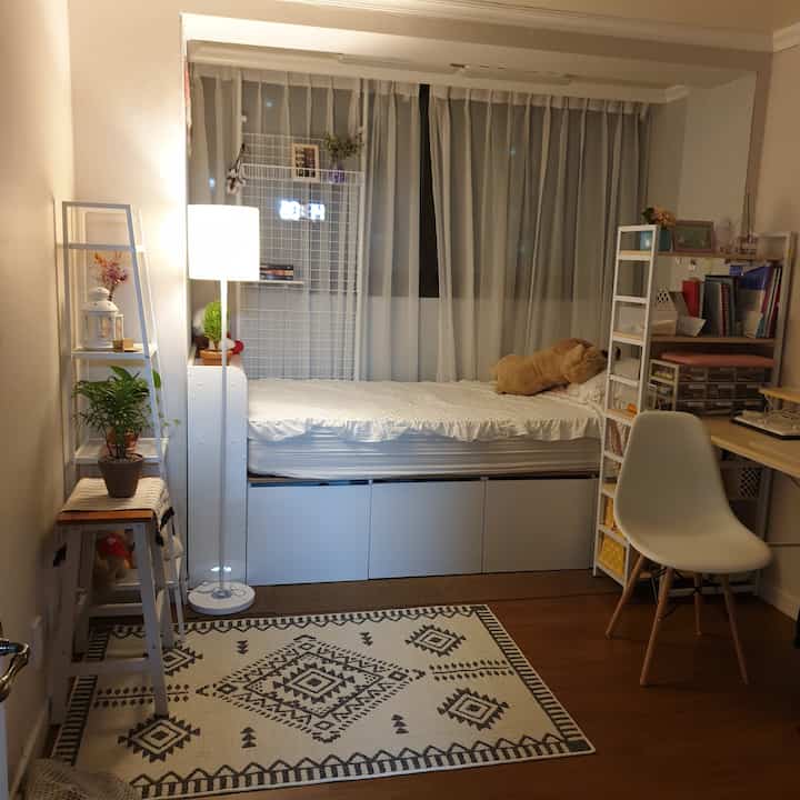 White and brown toned small bedroom featuring a bed, desk, shelves, and floor lamp in a cozy single household room