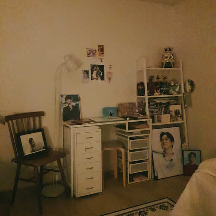White-toned bedroom featuring a desk, shelves, and drawer units in a cozy personal room