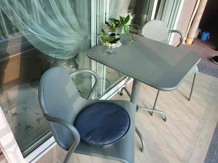 Natural-toned balcony featuring gray dining table and chairs creating a cozy outdoor space