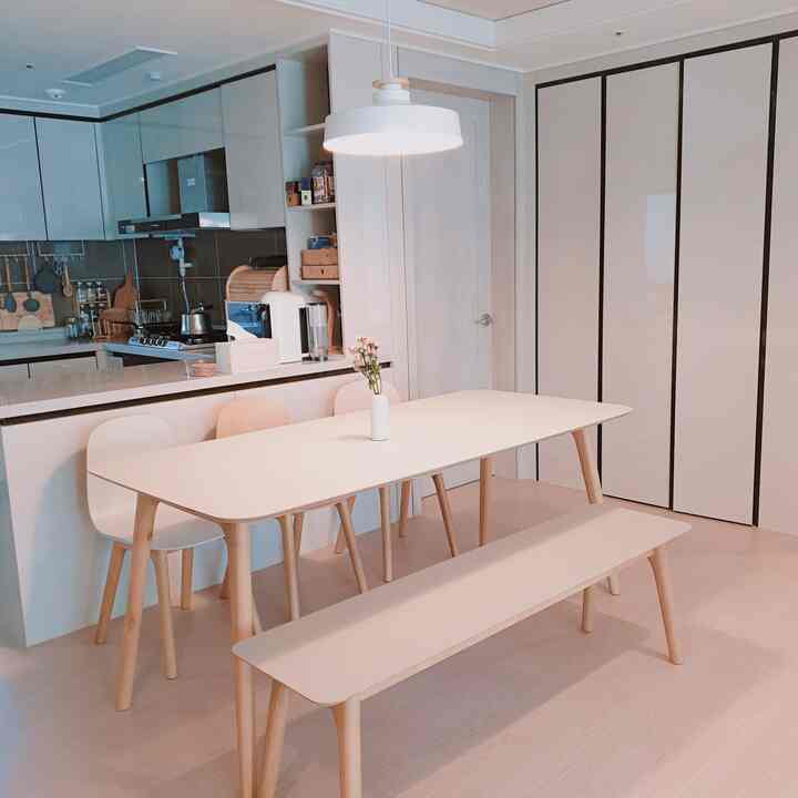 Clean kitchen and dining space featuring white and natural brown tones with a pendant light