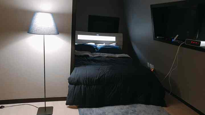 Cozy bedroom with natural-toned walls and floor, black bedding, and blue pillows