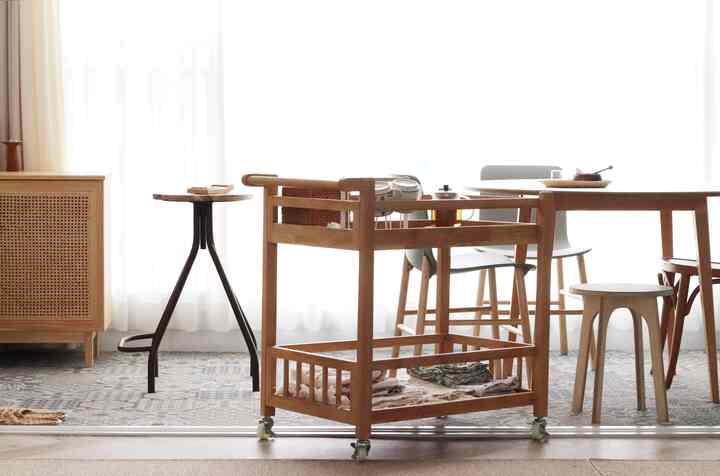 A cozy kitchen-veranda space in soft natural tones featuring a wooden trolley, round dining table, and stools with airy curtains