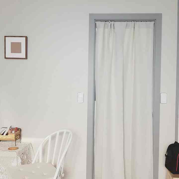 Bright, white-dominated entrance area featuring a white curtain and dining chair with a clean, minimalist atmosphere