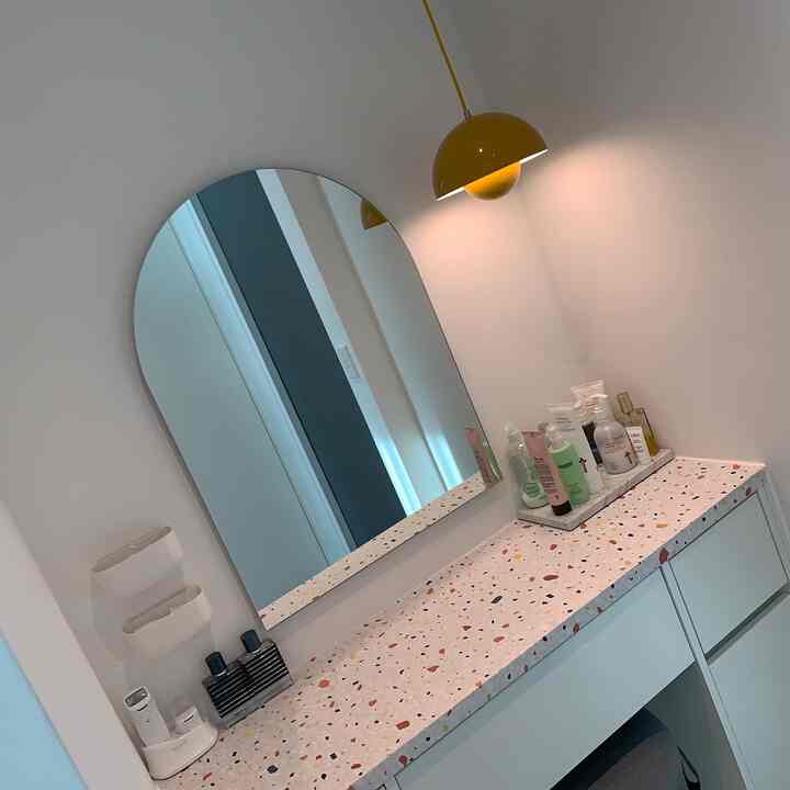 白い壁とミニマルなデザインの化粧台が配置されたウォークインクローゼット、黄色いペンダントライトが印象的な空間