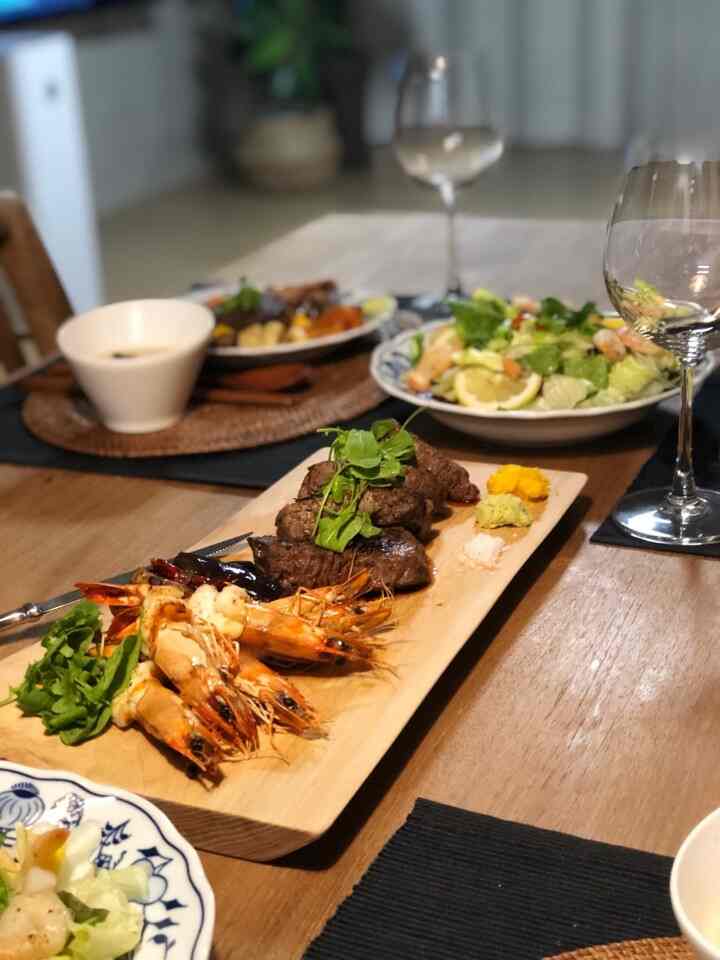 Natural wood-tone dining table with assorted dishes and wine glasses in a cozy home party setting