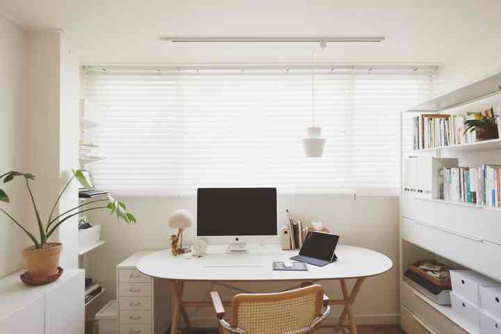 A practical white and wood tone study featuring a central desk and organized bookshelf in a clean space