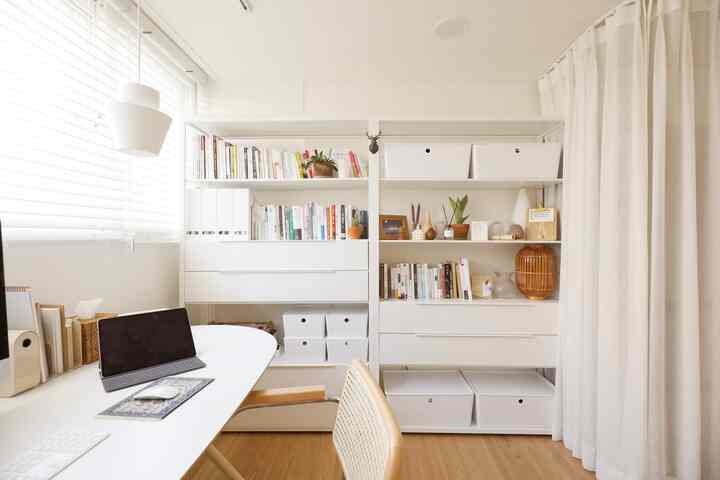 White and wood-tone home office featuring desk and bookshelves arranged neatly in a compact space
