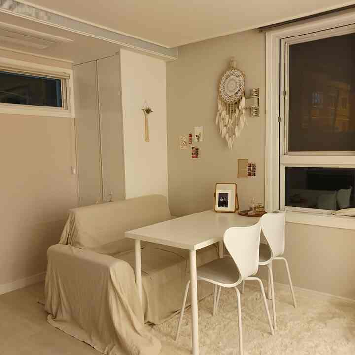 Beige and white toned studio dining room featuring sofa, dining table and chairs in a cozy setting