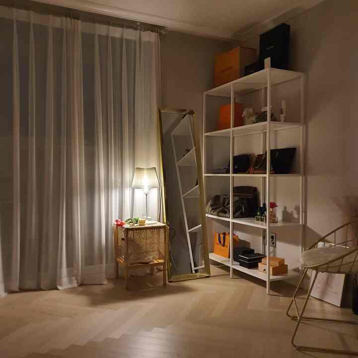 白とゴールドの色調のウォークインクローゼット、バッグ収納棚と全身鏡、照明が配置されたシンプルでナチュラルな雰囲気のインテリア