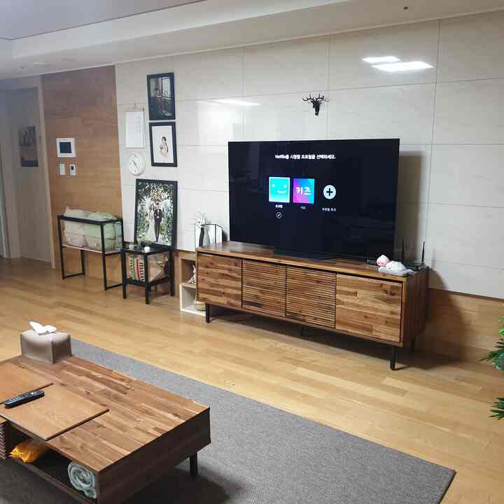 Natural wood tone and beige living room featuring TV stand, carpet, and console table creating a warm atmosphere