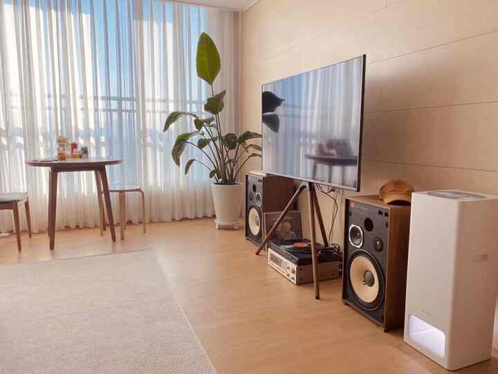 Living room with white and wood tones, featuring vintage speakers and a turntable creating a warm atmosphere