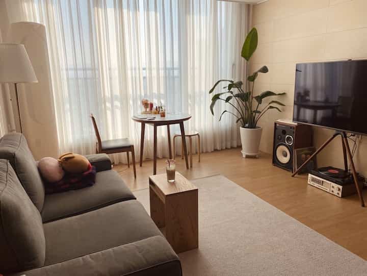 Natural wood tones and white blend in the living room, featuring a gray sofa and round table creating a cozy atmosphere