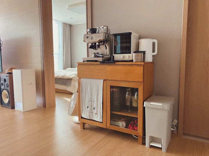 Wood tone and white kitchen space featuring a cabinet with coffee machine and microwave, creating a cozy atmosphere