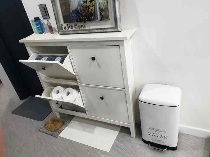 白色調のバスルーム隣接スペースに、イケアのシューズラックとペダル式ゴミ箱がすっきり配置された実用的な収納空間