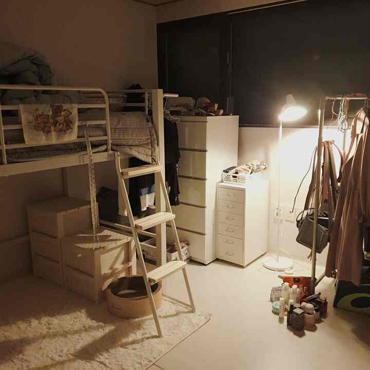 ナチュラルカラーのワンルーム、木製ハンガーラックとフロアランプが配置された雰囲気ある空間