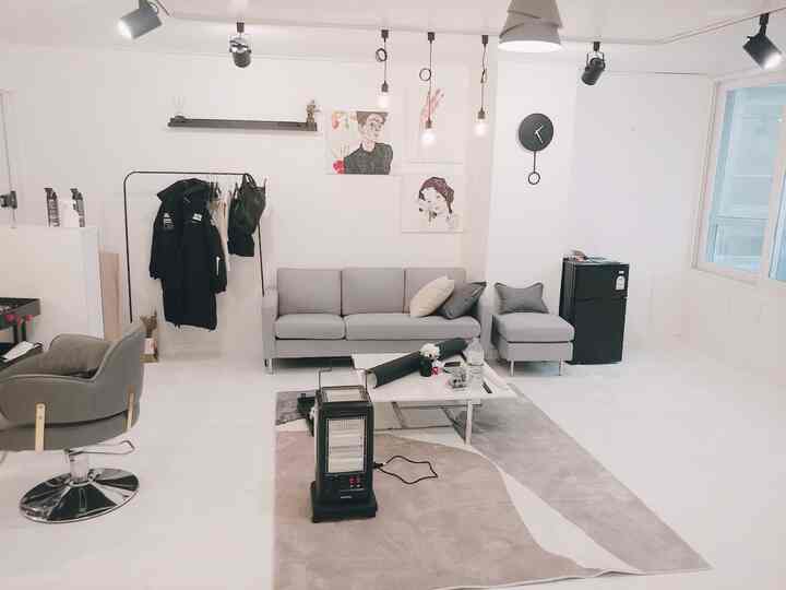 ホワイトとグレーのトーンの1人用ショップのリビング、モダンでシンプルなソファとラグが配置された清潔感のあるインテリア