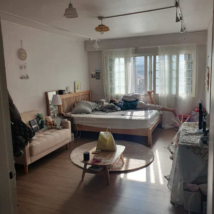 ナチュラルな色調の寝室、木製ベッドとベージュのソファが配置された穏やかな週末の居心地の良い空間