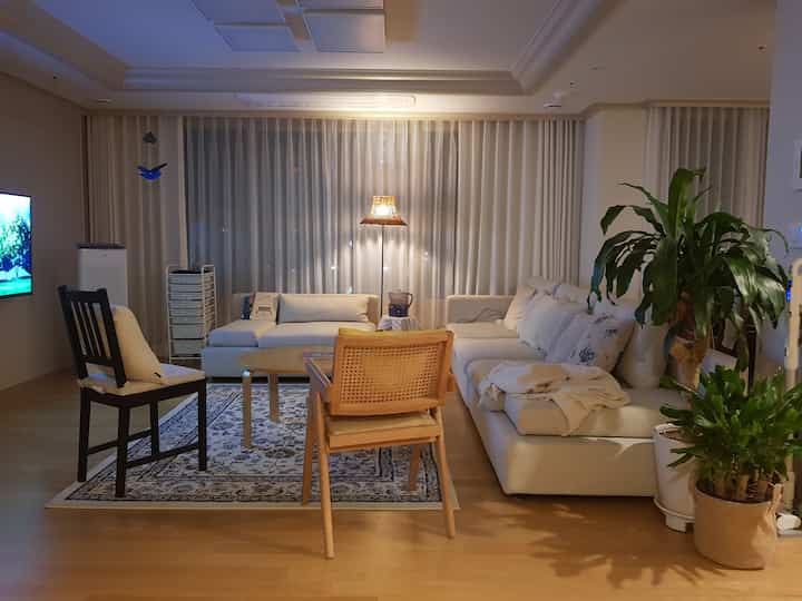Natural-toned living room for 4 people, featuring modular sofa, rattan chair, and floor lamp creating a warm atmosphere