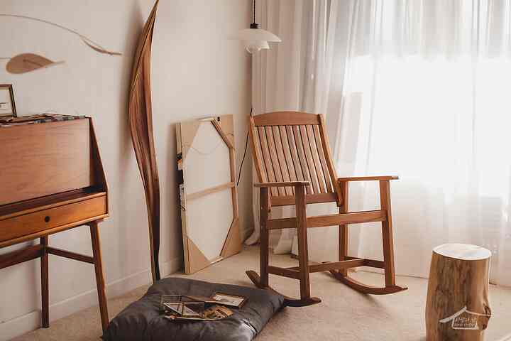 Natural living room featuring wood tone rocking chair and white curtain with soft lighting