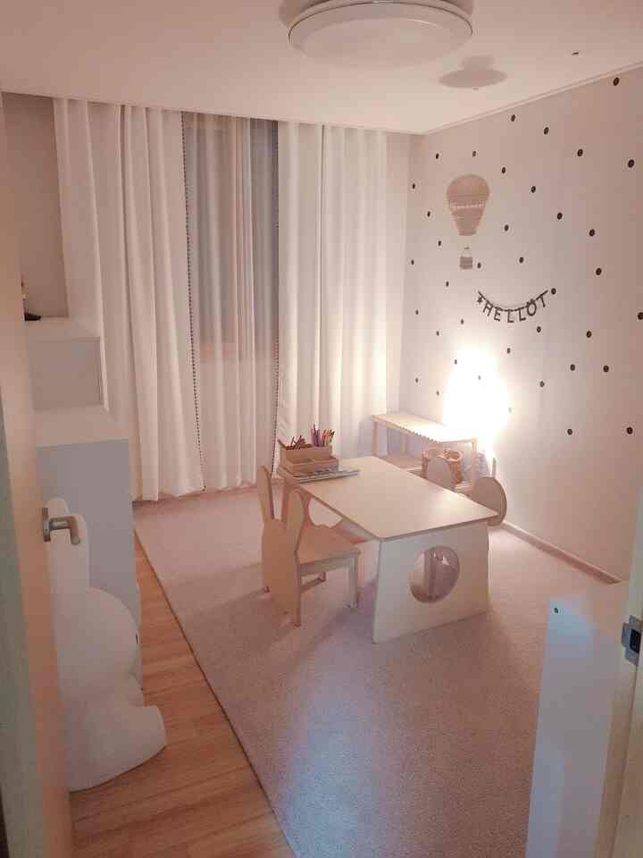 Natural beige toned kids' room featuring children's desk and chairs in a cozy play and study space