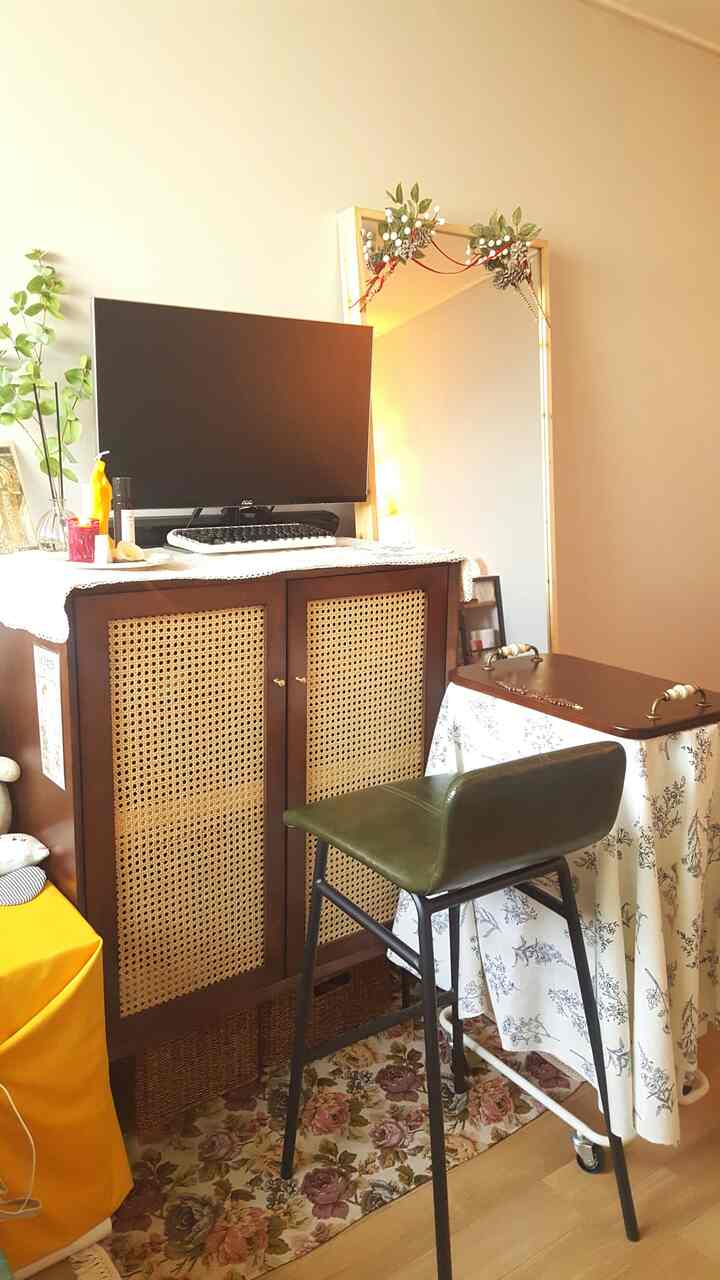 Natural wood tones and vintage carpet define this single household home office space featuring a bar stool and storage cabinet for a cozy workspace