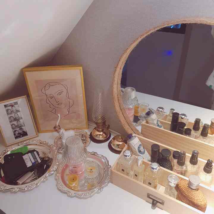 Natural tone dresser with round mirror and decorative items arranged on top, creating a cozy vanity space