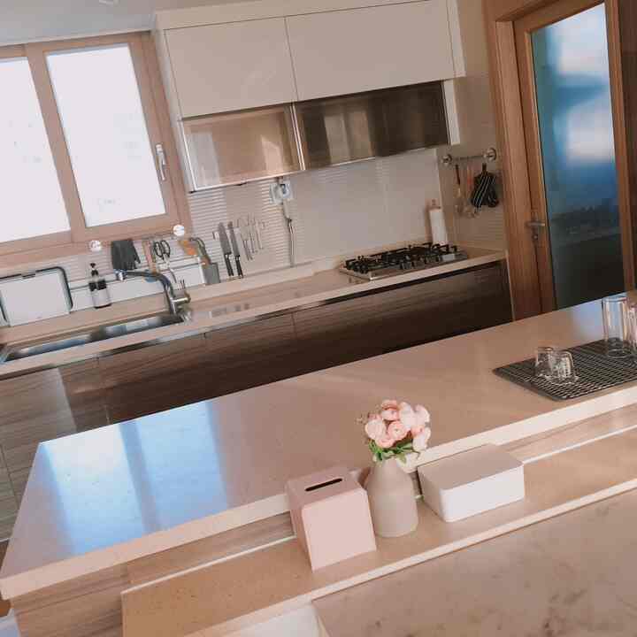 Modern kitchen in soft white and brown tones featuring a marble countertop and organized cooking utensils in a clean space