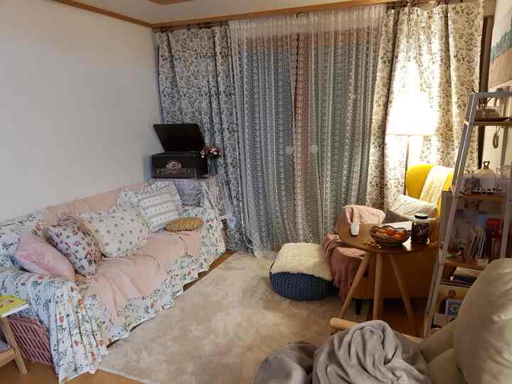 A warm beige living room with floral patterns, featuring a yellow armchair and assorted cushions creating a cozy atmosphere