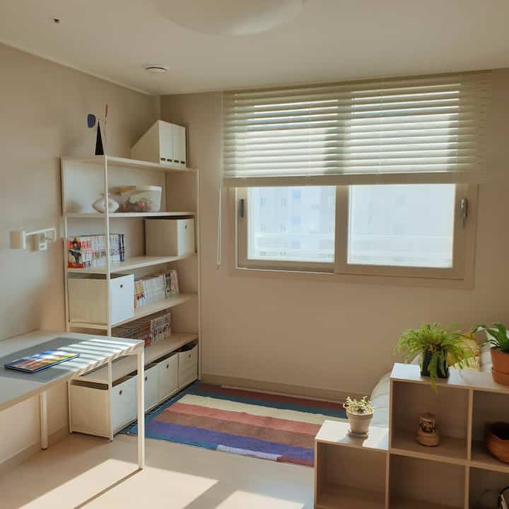 Bright white and natural color study featuring bookshelf and desk, neat reading and working space