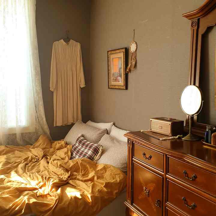 Cozy bedroom featuring warm yellow bedding and elegant brown antique furniture with soft natural light