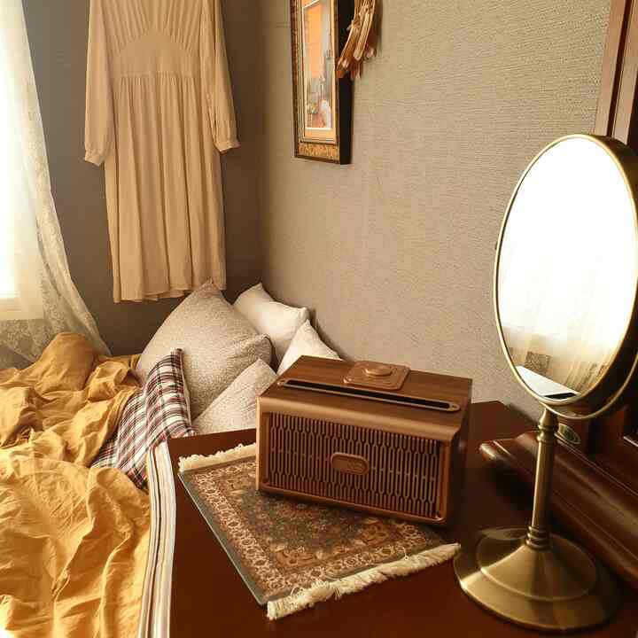 Beige and wood-tone bedroom featuring mustard duvet cover, wood Bluetooth speaker, and a round mirror creating a cozy atmosphere