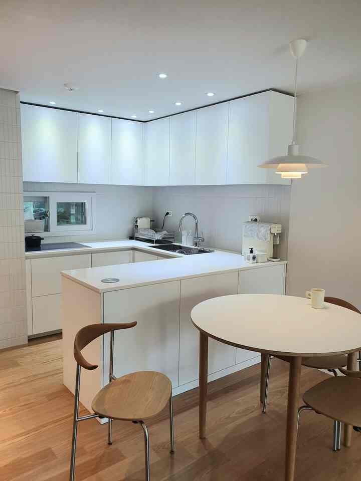 Modern kitchen in white and natural wood tones with a clean space featuring a round dining table and pendant lighting