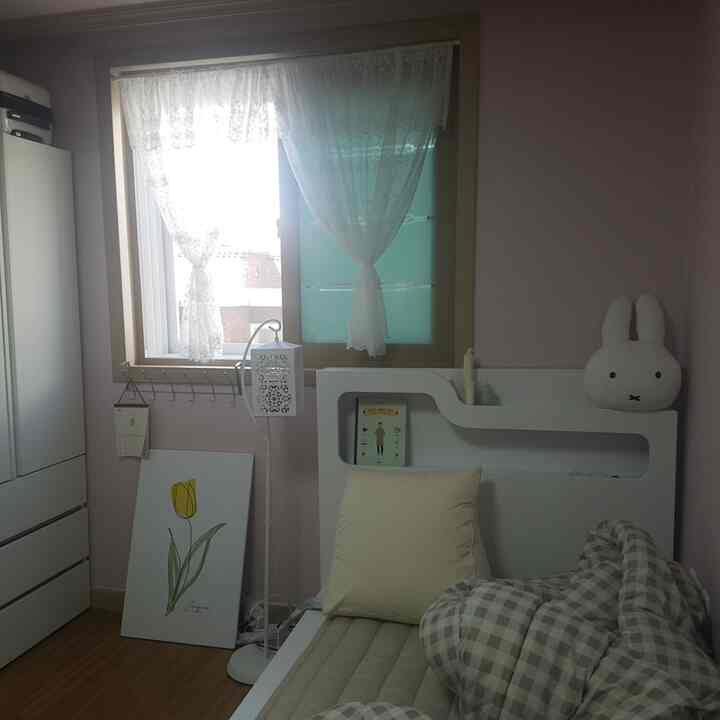 ピンク色の壁と白い家具が配された6畳サイズのシンプルな子供部屋