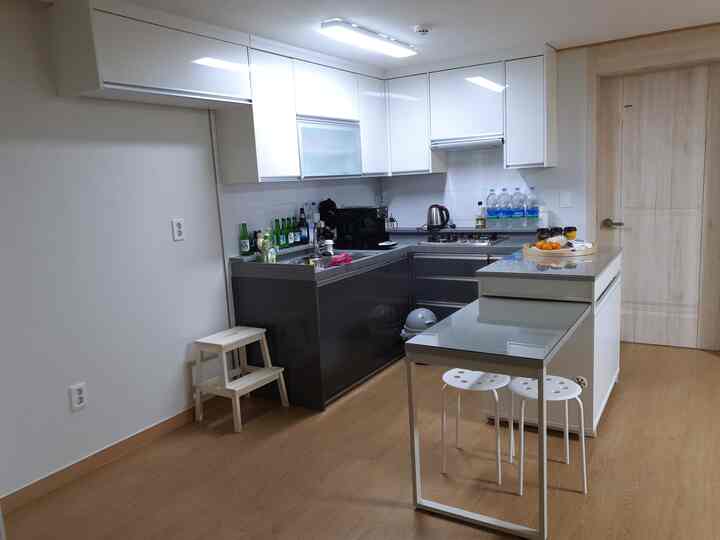 A compact kitchen space featuring white and wood tones, equipped with an extendable island dining table and storage cabinets in a clean modern style