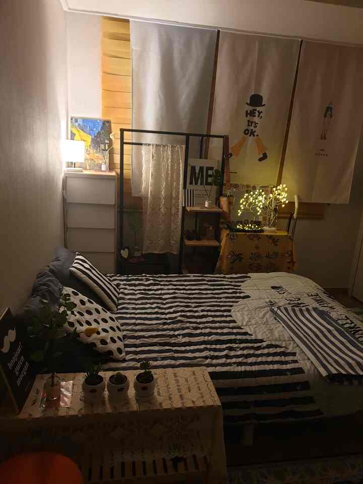 Cozy natural modern bedroom for single household featuring white and black striped bedding with ambient lighting