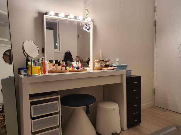 White-toned walk-in closet and powder room featuring IKEA furniture, vanity, and stools in a neat setting
