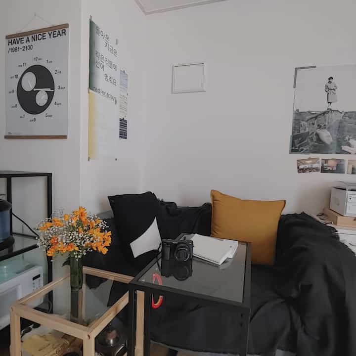 A small home office with white walls and a black sofa, blending modern and vintage styles