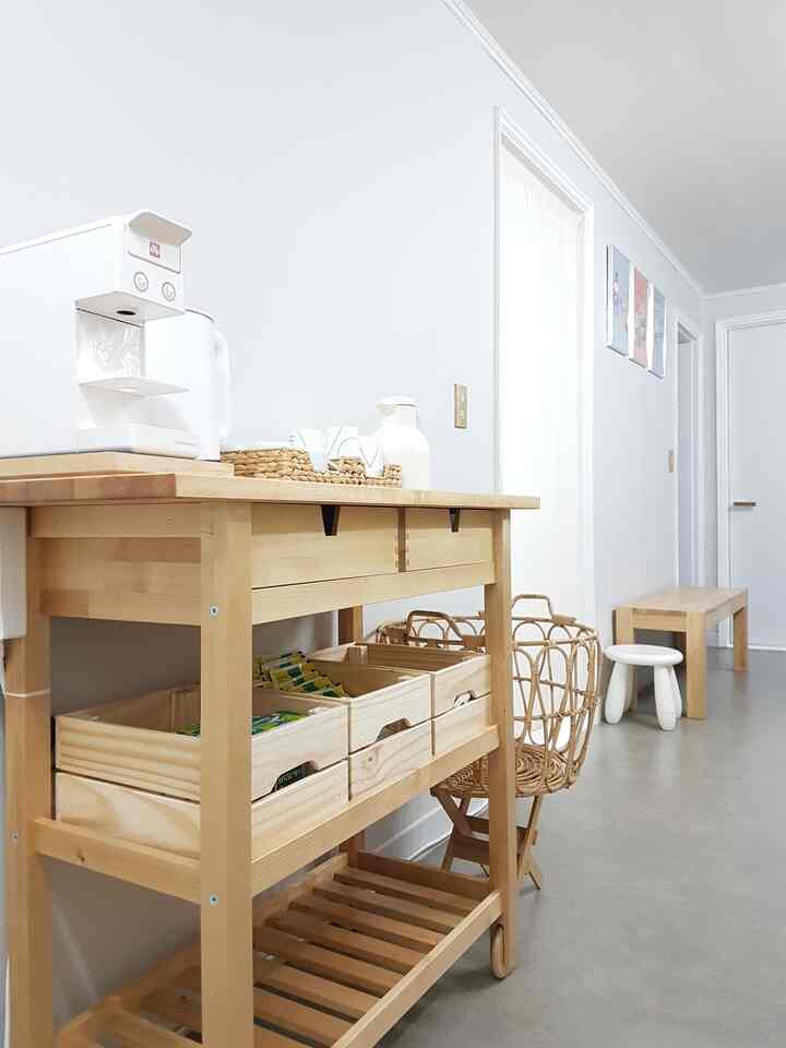 Bright white and natural wood-toned narrow hallway space featuring a kitchen cart with coffee machine, creating a clean home cafe atmosphere