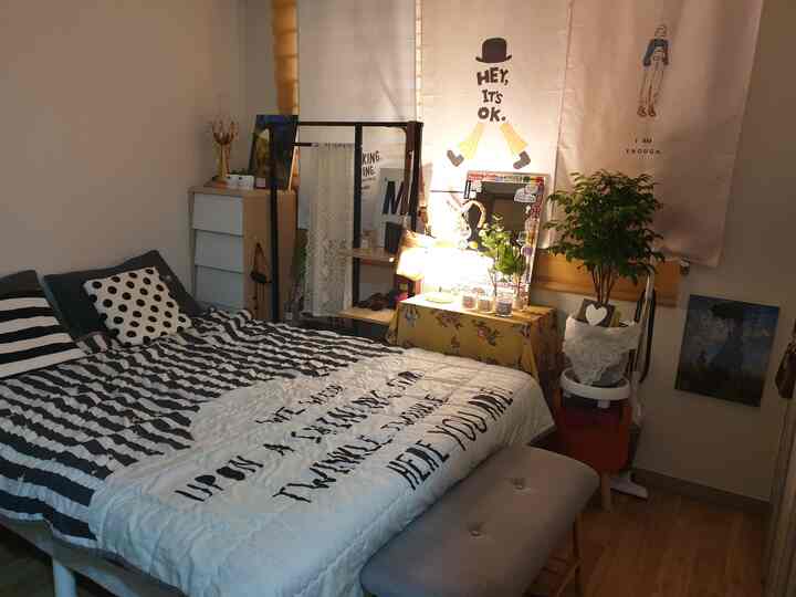 白と茶色のトーンの寝室、ストライプの寝具とナチュラルな家具が配置された落ち着いた空間