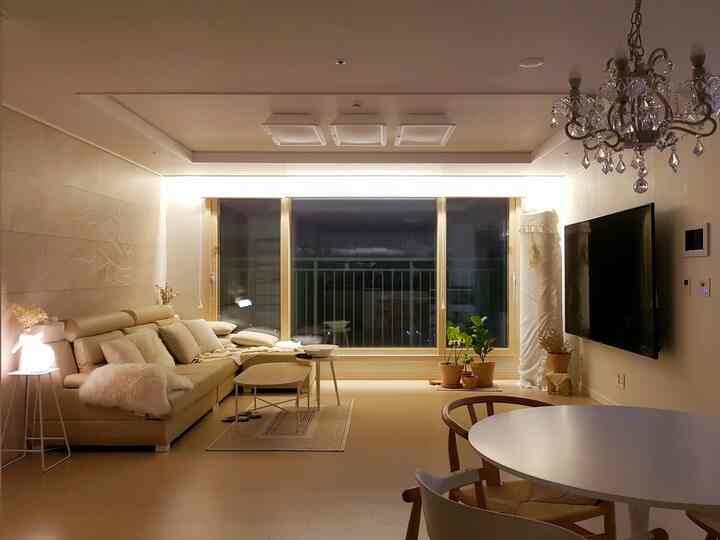 Beige-toned living and dining room featuring modern natural furniture and ambient mood lighting in a cozy newlywed home